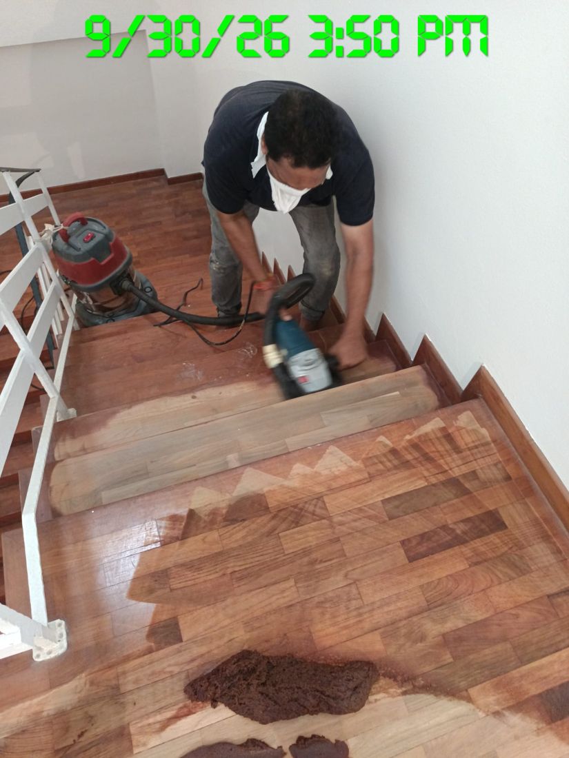 Technician sanding old varnish off a timber staircase, half done